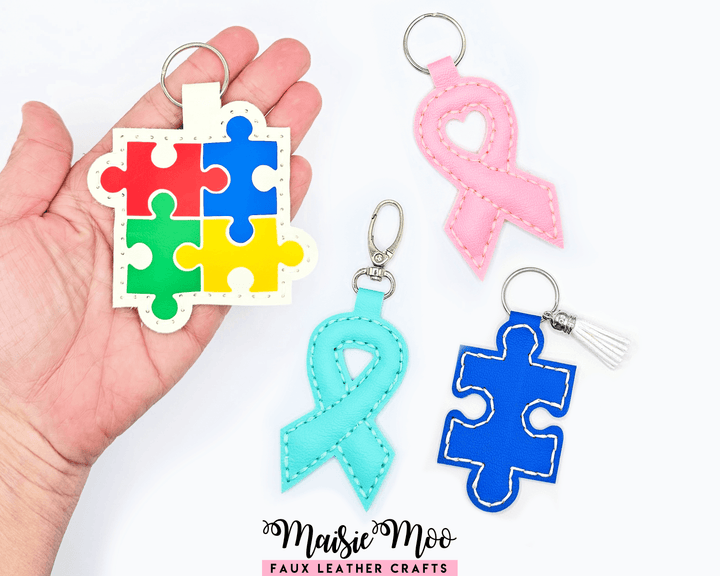 Colorful awareness ribbon keychain collection featuring puzzle pieces and ribbons in various colors.