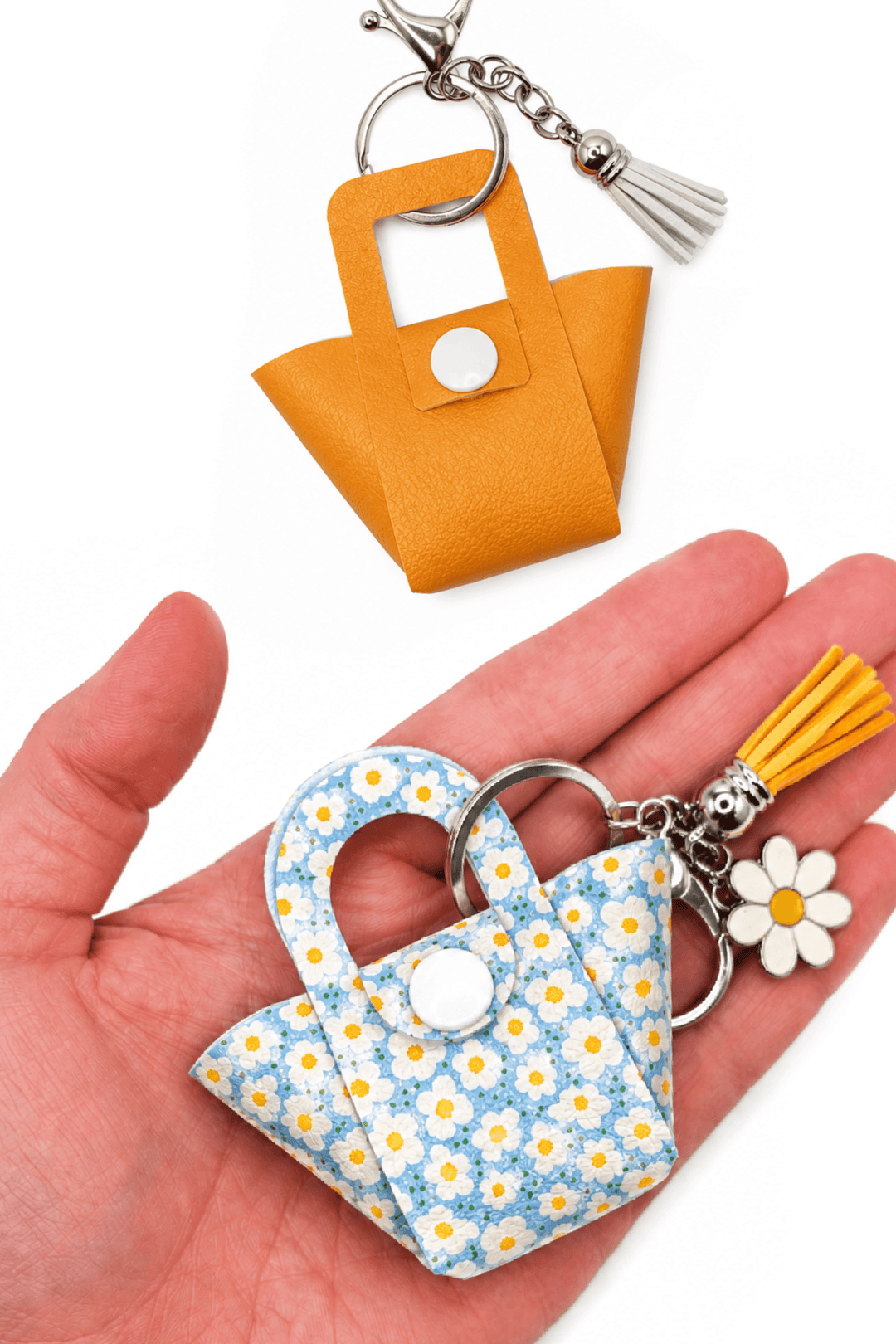 Hand holding two Tote Bag Charm keychains, one yellow leather and one floral design, showcasing cute miniature style.
