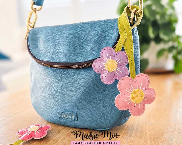 Flower Blossom Bag Charm SVG, Faux Leather Flower attached to a stylish blue bag, showcasing vibrant colors and designs.