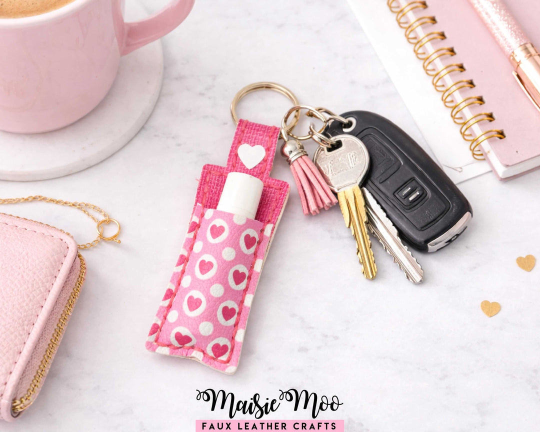 ChapStick Holder Keychain with pink heart pattern, keyring, and keys on a stylish workspace.