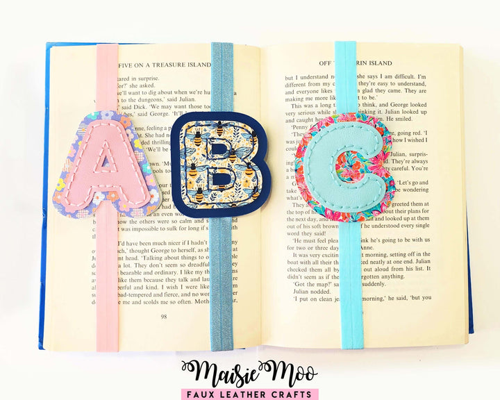 Alphabet Bookmark SVG Set for Cricut featuring stitched initial bookmarks A, B, C on an open book.