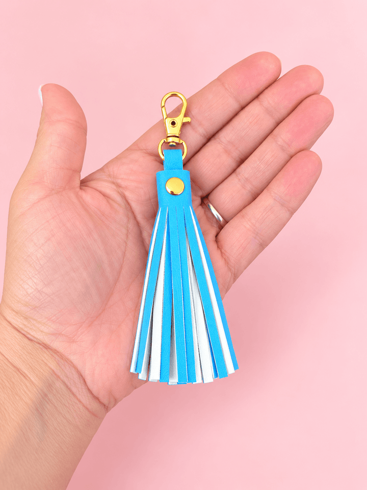 FREE Faux Leather Rivet Tassel Pattern – 4 Sizes keychain in hand, showcasing a blue faux leather tassel with clip.