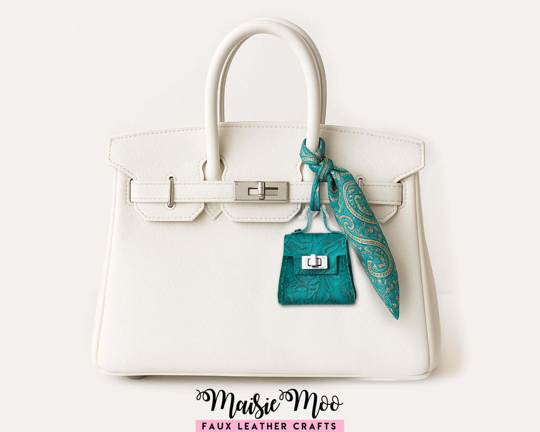 Purse Bag Charm Hand Sewing Pattern displayed on a stylish white handbag with turquoise scarf.