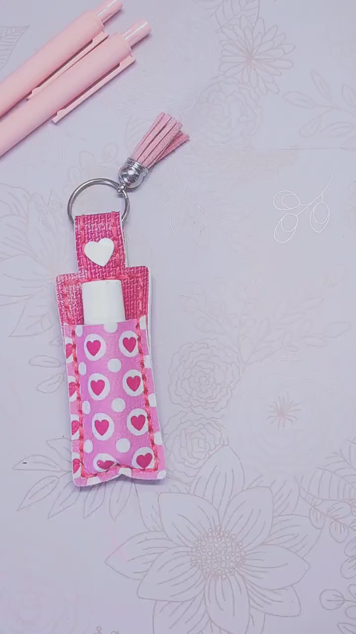ChapStick Holder Keychain with pink hearts pattern and tassel, perfect for gifting or personal use.